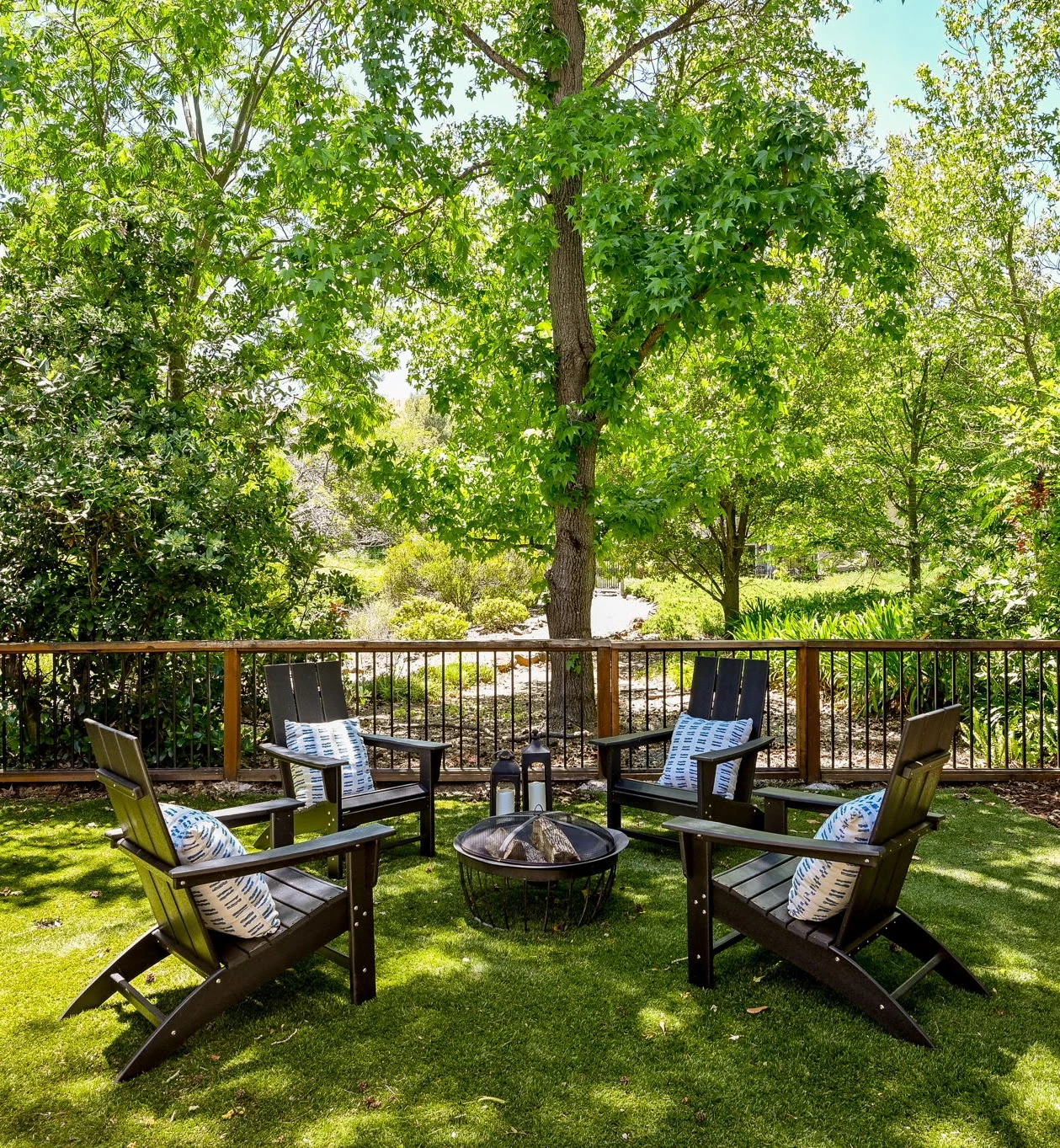 Outdoor chairs and a fire pit on a deck surrounded by trees