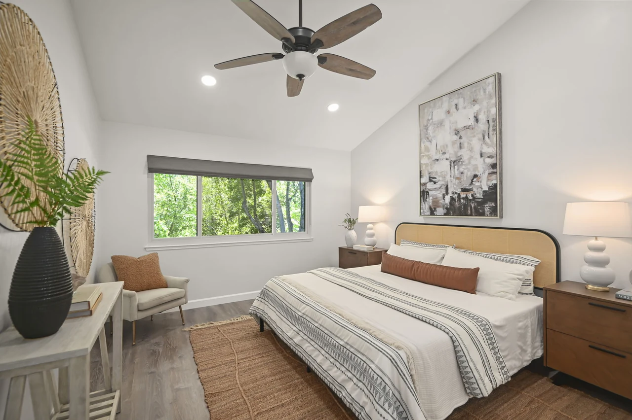 Bedroom with a wood headboard, ceiling fan and wide window