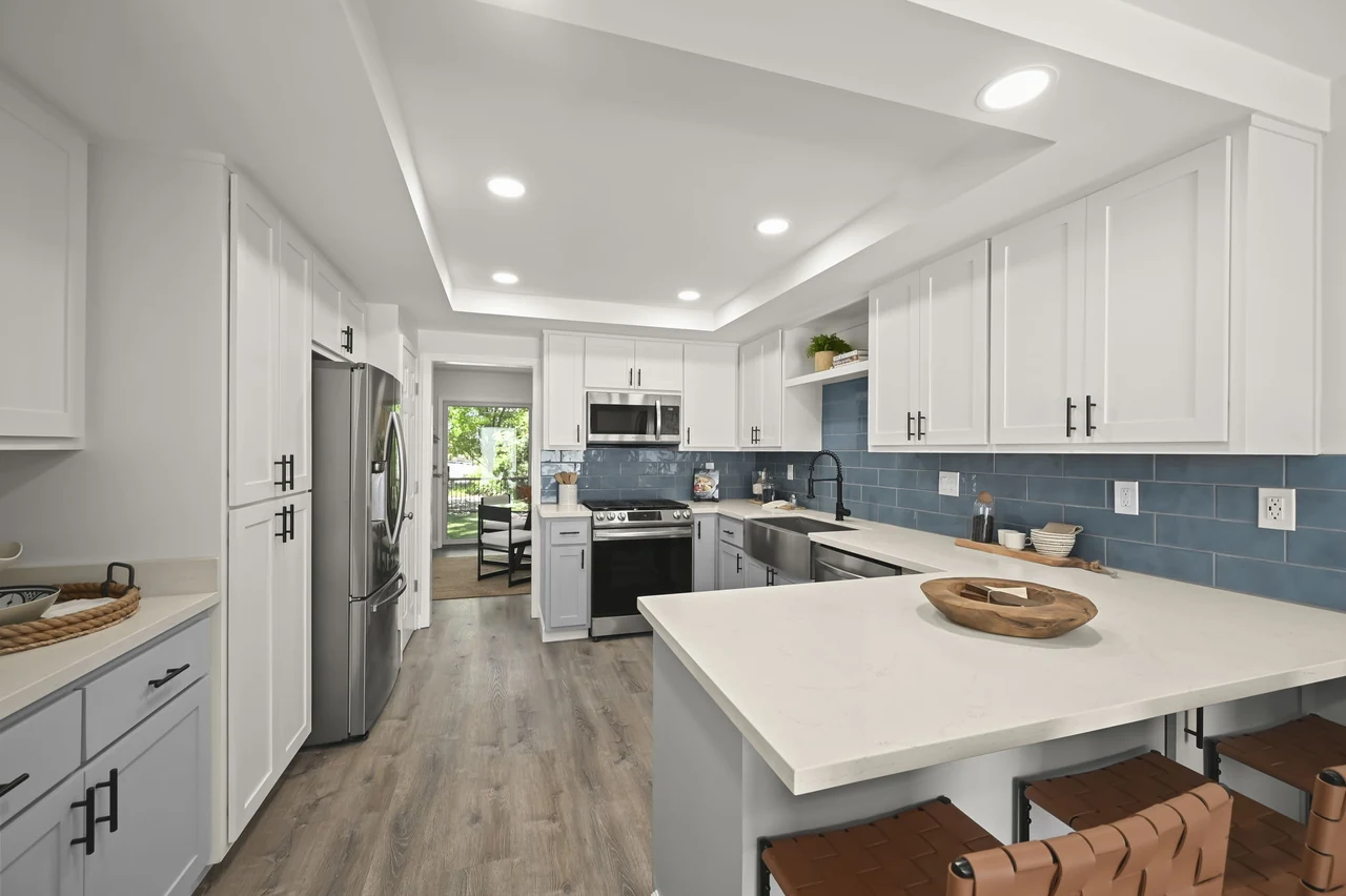 Kitchen with a white island, blue backsplash and wood-look flooring
