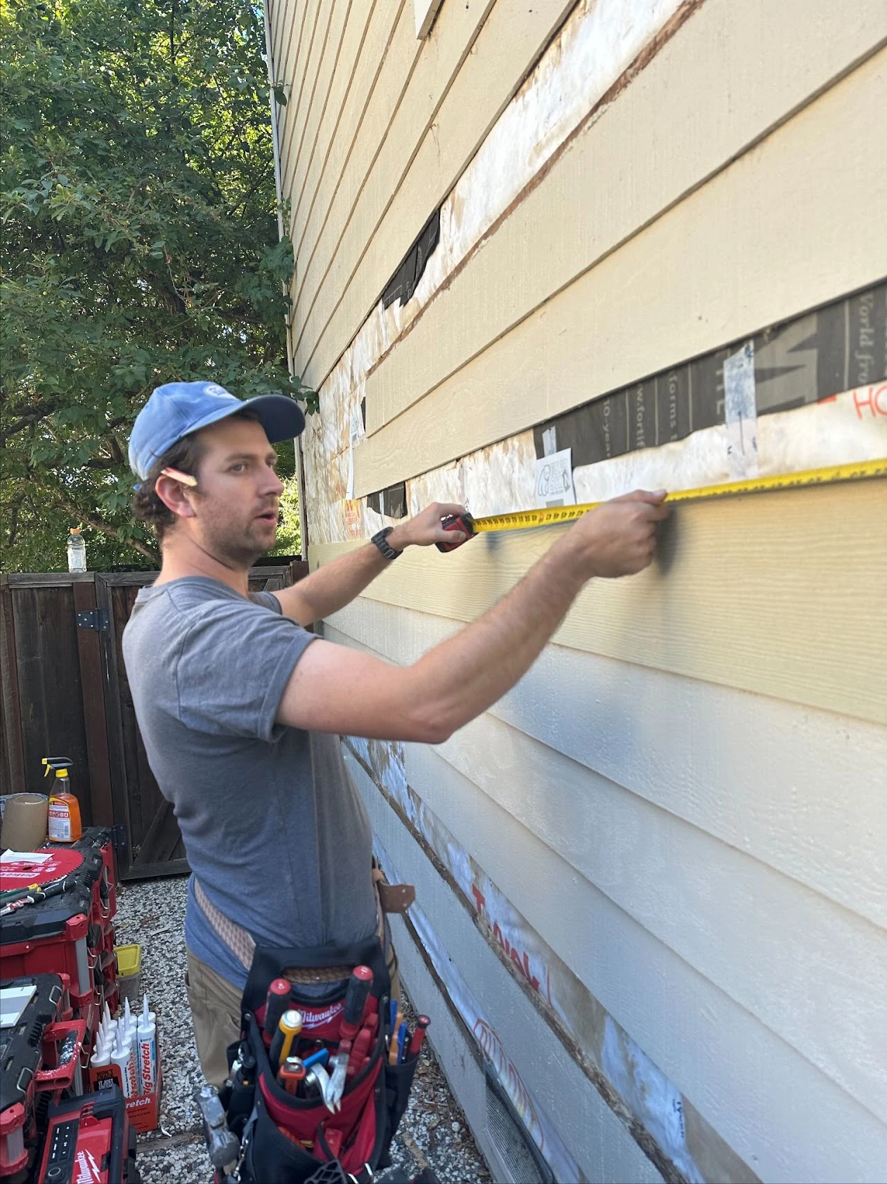 Worker fitting a horizontal siding board on an exterior wall