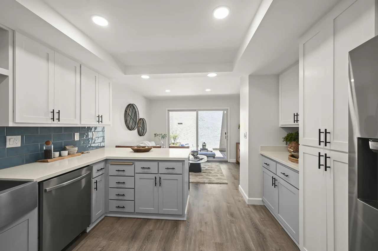 Kitchen view along white cabinets toward a bright sitting area